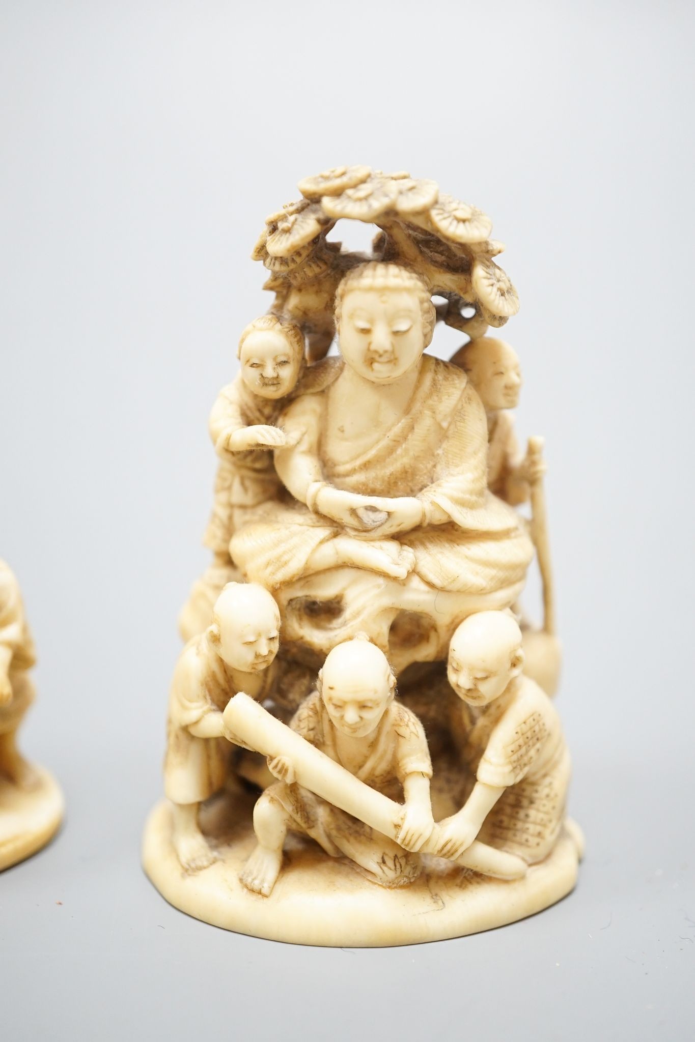 Two Japanese ivory okimono-netsuke of Buddha and attendants and a group of artisans, Meiji period, both signed, tallest 7cm